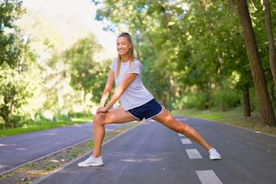 Portrait of smiling young woman on road against trees