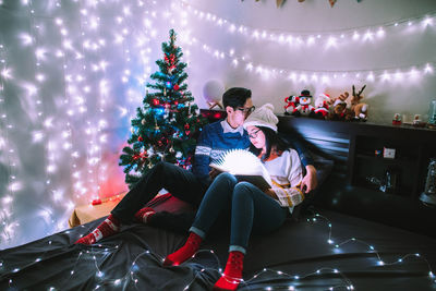 People sitting in illuminated christmas tree