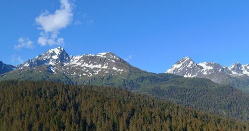 Scenic view of snowcapped mountains against blue sky