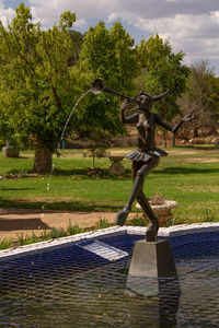 Statue by fountain against trees