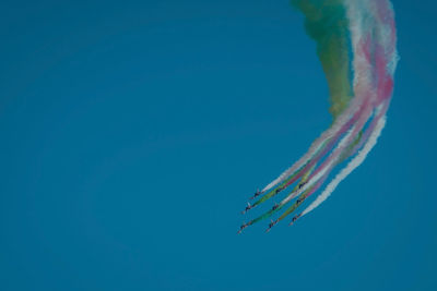 Low angle view of airshow against clear blue sky