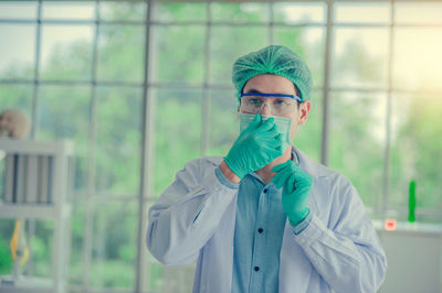 Portrait of scientist wearing surgical mask and cap standing in laboratory
