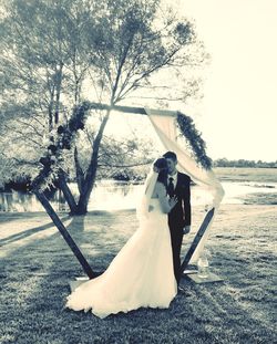 Woman holding umbrella while standing by tree