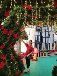 Portrait of woman standing by christmas tree