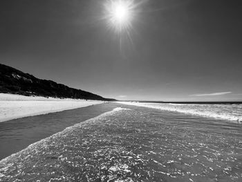 Scenic view of beach against sky on sunny day