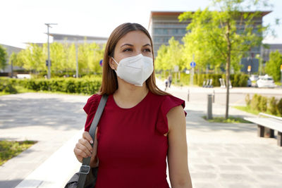 Portrait of beautiful young woman standing against city in background