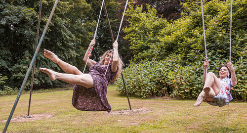 Beautiful middle aged couple of female friends swinging on children's swings in a french park