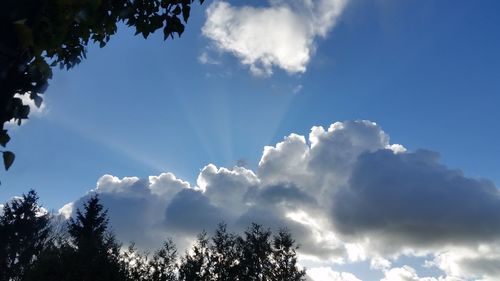 Low angle view of sunlight streaming through clouds