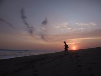 Man on beach against sky during sunset