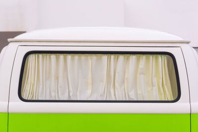 Curtained window of a bright white and green retro volkswagen van close up