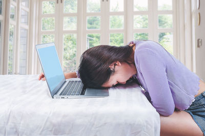 Rear view of woman using mobile phone at home