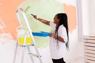 Side view of young woman standing against wall