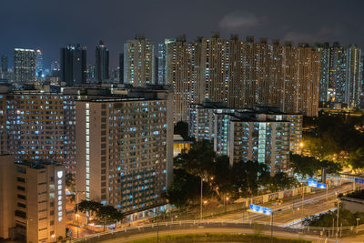 Illuminated modern buildings in city against sky at night