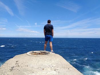 Rear view of man looking at sea against sky