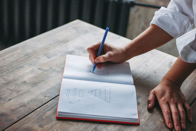 High angle view of woman drawing on book at table