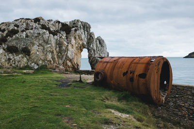 Abandoned rusty car on beach against sky