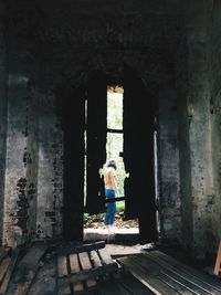 Rear view of woman standing by old building