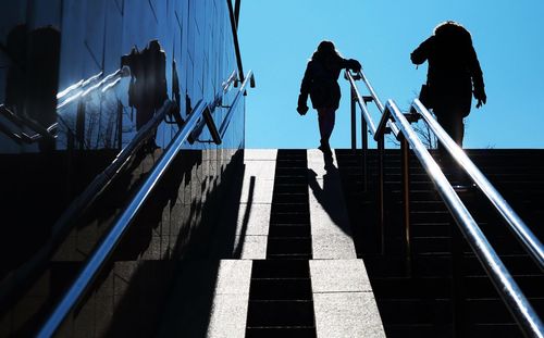 Low angle view of people on staircase against sky in city