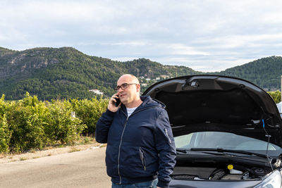 Caucasian young adult calling the roadside assistance service on the phone, 