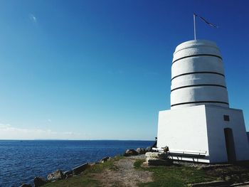 Lighthouse by sea against sky