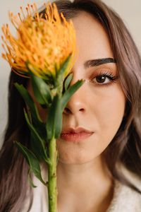 Close-up portrait of beautiful young woman holding yellow flower