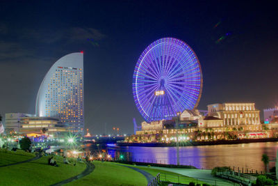 Illuminated ferris wheel in city at night