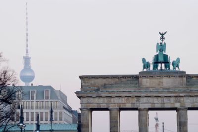 Statue in city against clear sky