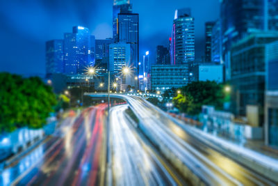 Light trails on road amidst buildings in city at night