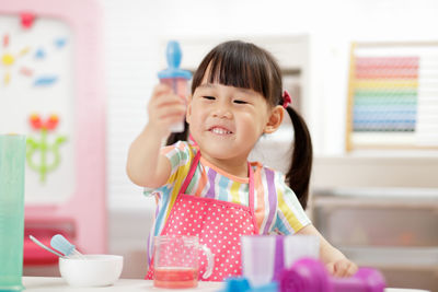 Portrait of cute girl holding camera at home