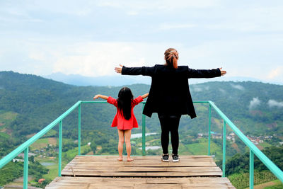 Rear view of women standing on railing against sky