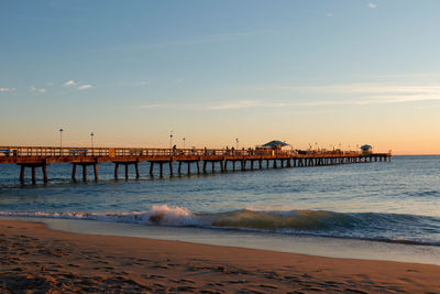 Pier over sea against sky during sunset