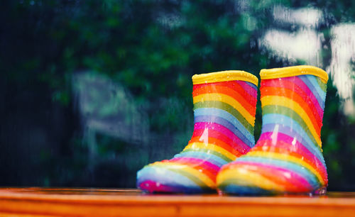 Close-up of multi colored rubber boots on table during rainy season