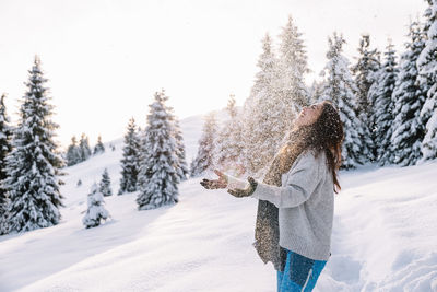 Woman having fun while hiking in the snow during winter, at sunset time.