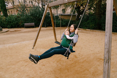 Full length of smiling boy on swing at playground