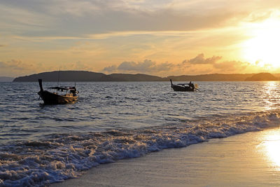 Ao nang, thailand. sunset on the beach of the village. two long tail boat wait the tourists.