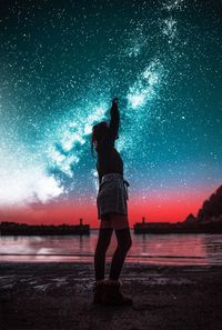 Rear view of woman standing at beach against sky