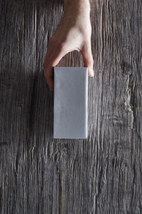 Directly above shot of hand holding paper on table