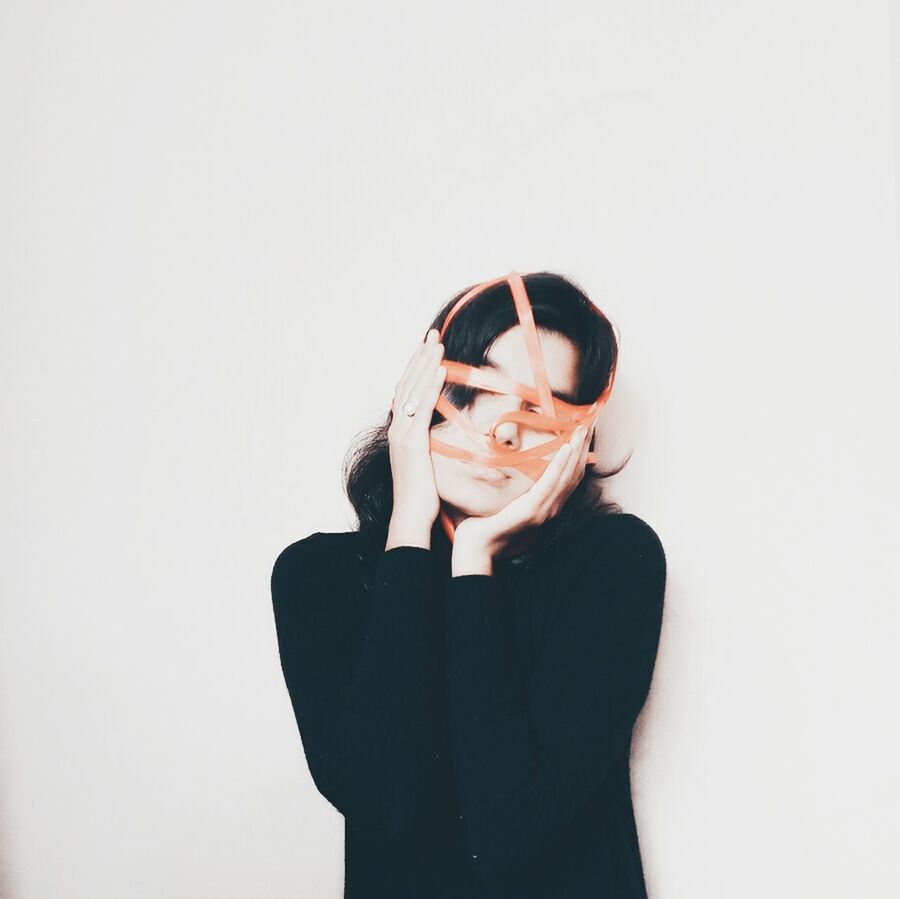 YOUNG WOMAN WEARING EYEGLASSES AGAINST WHITE BACKGROUND