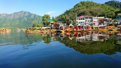 Scenic view of lake by trees and houses against sky