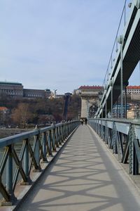 Footbridge amidst buildings in city against sky