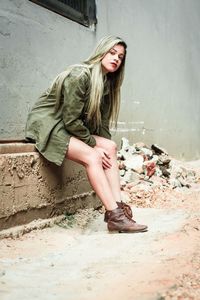 Portrait of young woman sitting on wall