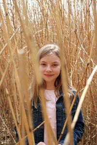 Portrait of smiling girl standing amidst dried plants