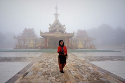 Full length of woman standing in temple during foggy weather 