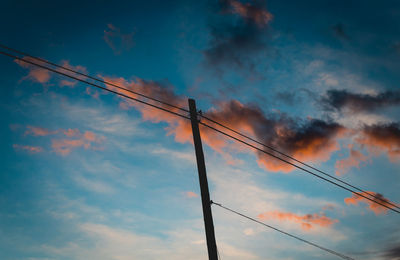 Low angle view of silhouette power lines against sky
