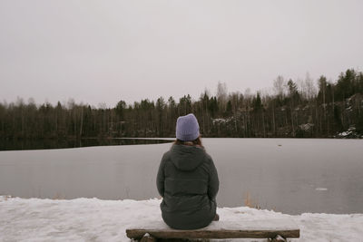 Rear view of woman standing on snow covered landscape against sky