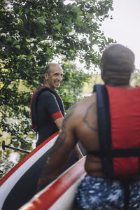 Men holding paddleboards while talking to each other