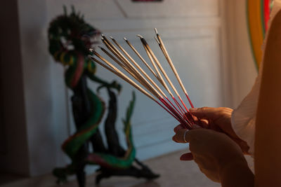 Cropped hands of woman holding incense sticks in temple