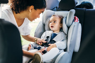 Baby sitting in car while looking at mother