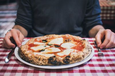 Midsection of man with pizza at table