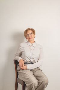 Young woman sitting on chair against white background